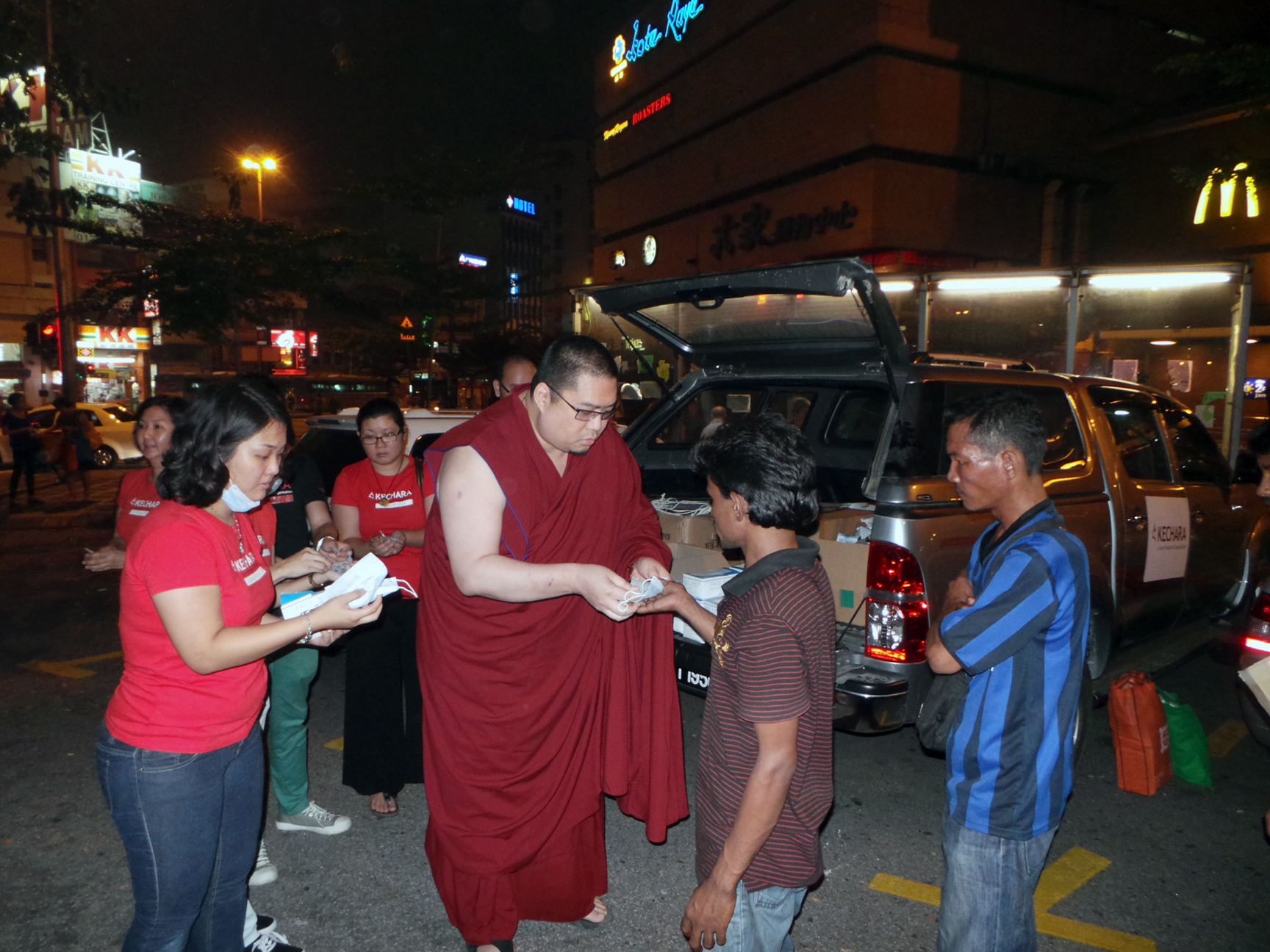 Rinpoche distributing in Cahaya Suria