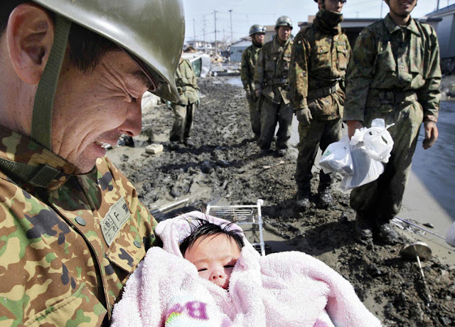 A 4-month-old baby girl in a pink bear suit is miraculously rescued from the rubble by soldiers after four days missing following the Japanese tsunami.