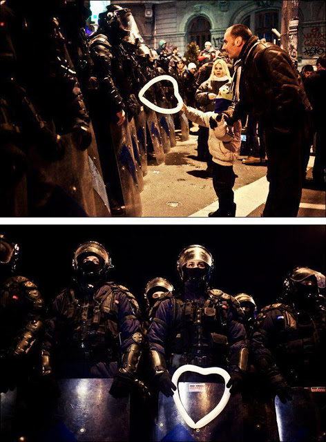 A Romanian child hands a heart-shaped balloon to riot police during protests against austerity measures in Bucharest.
