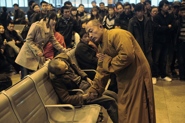 A monk prays for an elderly man who had died suddenly while waiting for a train in Shanxi Taiyuan, China.